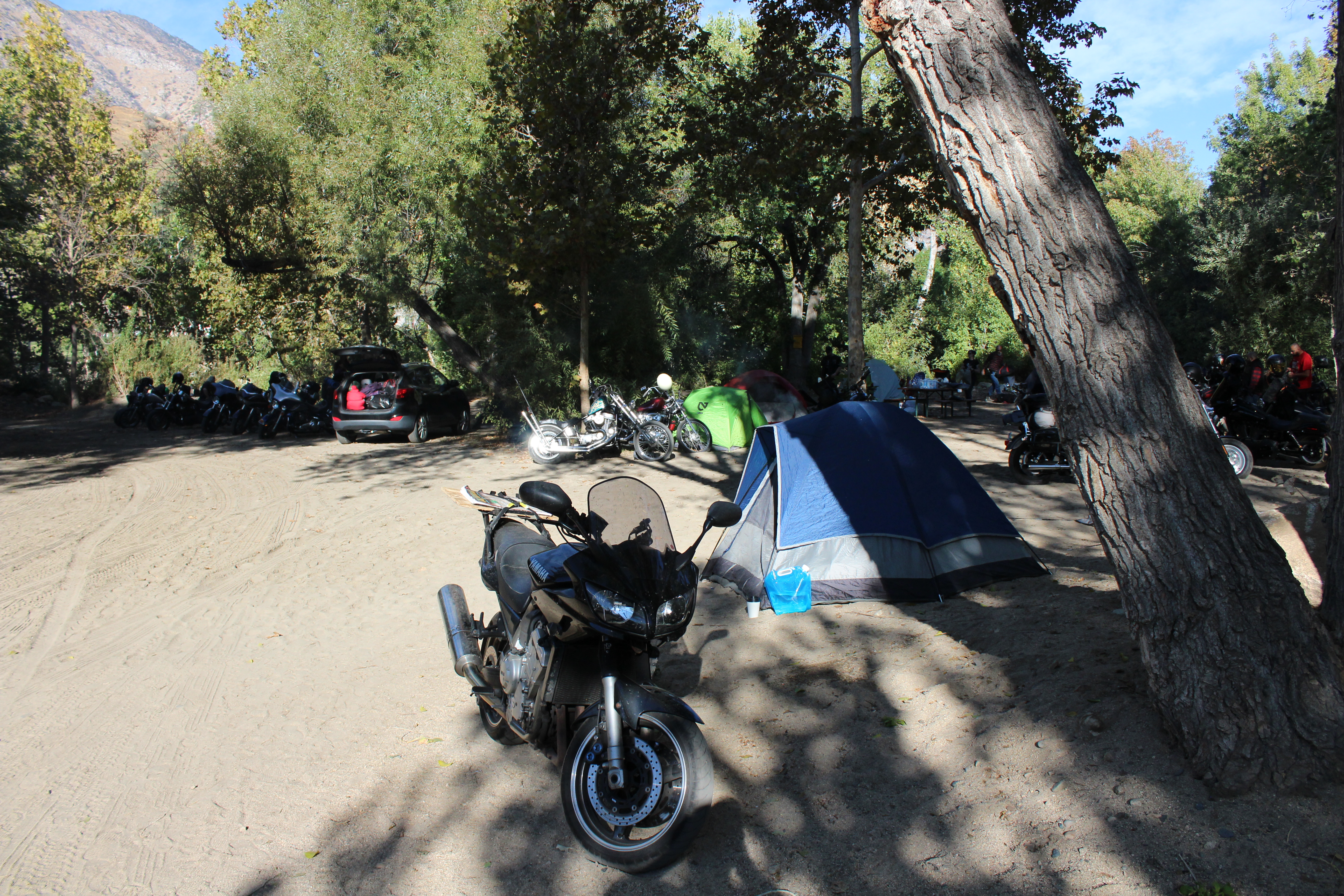 A motorcycle next to a tent in a campground by a river